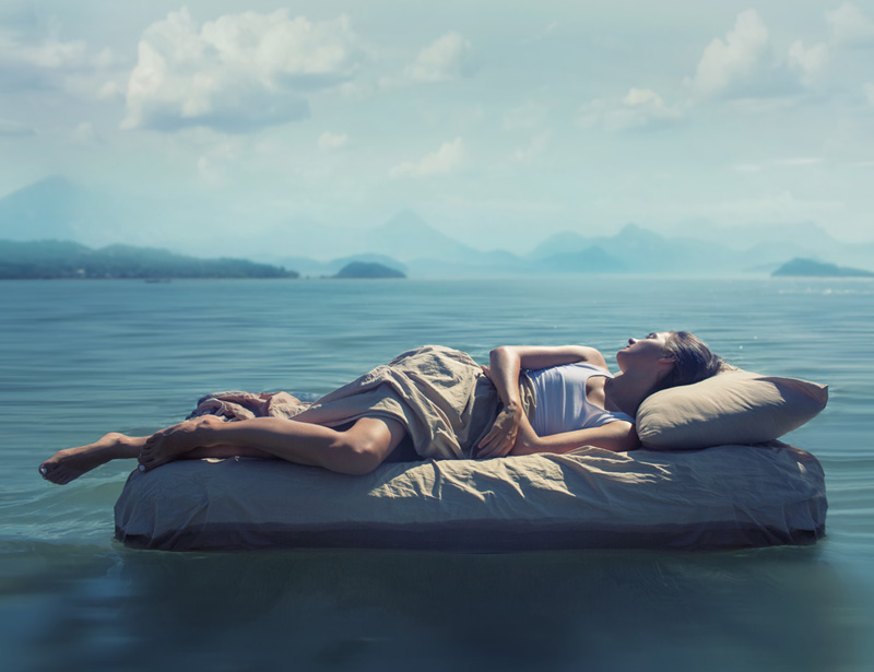 Chica en una cama flotando en un mar. Sensación de frescor